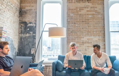Team brainstorming in a modern office with laptops and coffee, discussing strategy and collaboration ideas