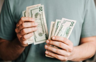 Close-up of a person counting US dollar bills indoors. Financial concept